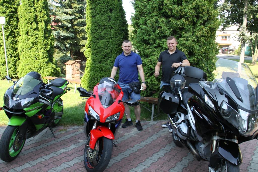 Zielony, czerwony i czarny motocykl, w tle dwie uśmiechnięte osoby