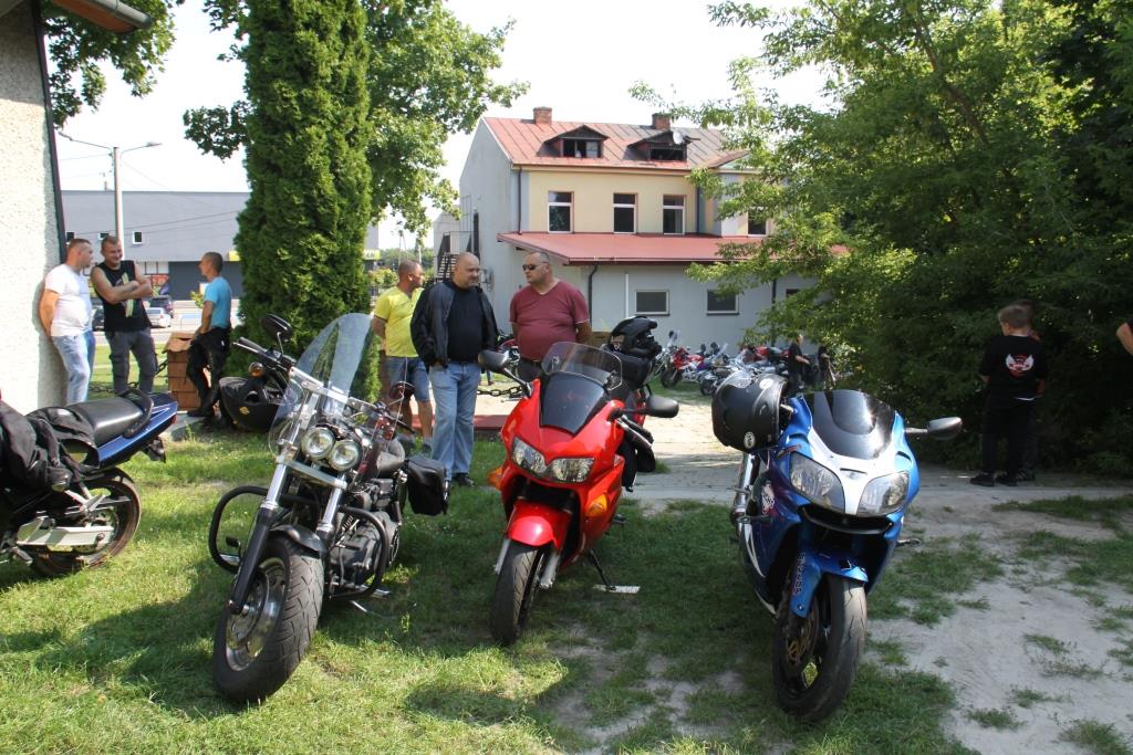 Motocykle stojące na trawniku, w tle stojące i rozmawiające osoby