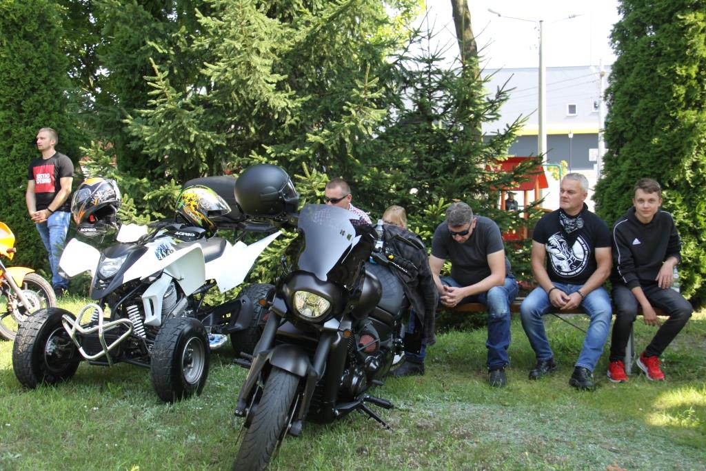 Motocykl i kład. Na ławce siedzą ludzie.