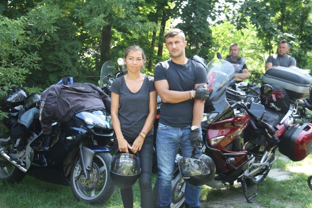 Dwójka uśmiechniętych motocyklistów na tle motorów