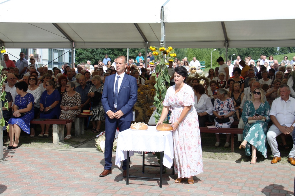 Starostowie dożynek z bochenkami chleba, w tle goście