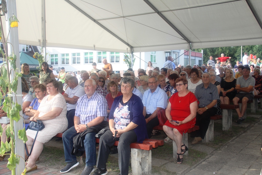 Widzowie oglądajacy występy na scenie, ludzie siedzą pod zadaszeniem