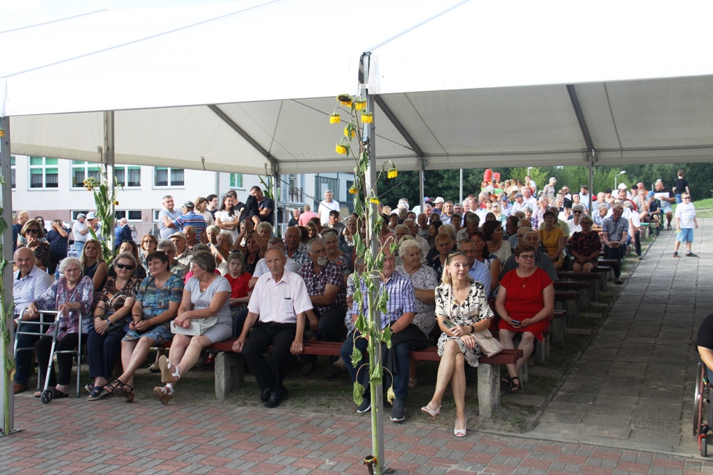 Widzowie oglądajacy występy na scenie, ludzie siedzą pod zadaszeniem