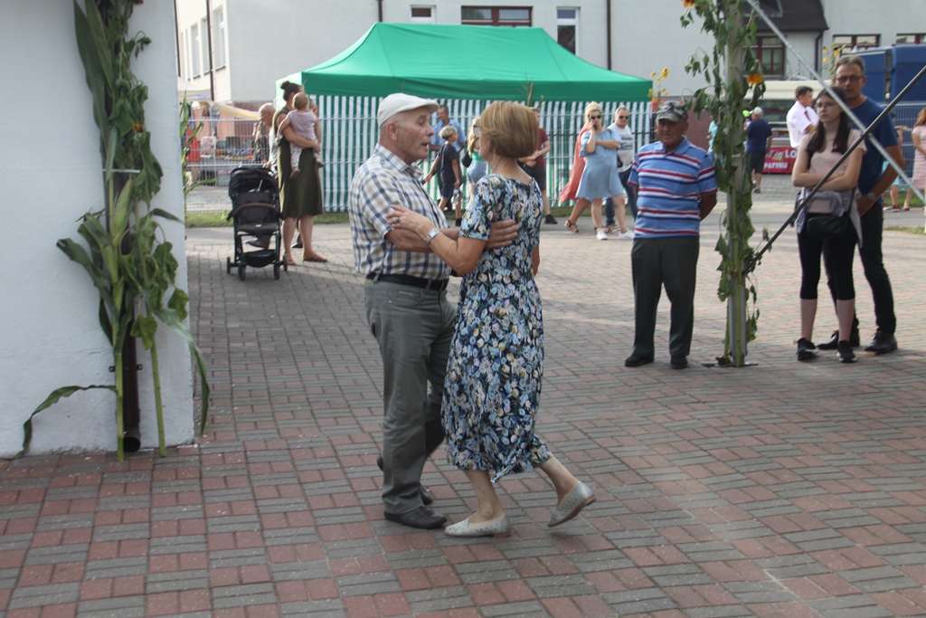 Para tańcząca obok sceny, w oddali przyglądające się temu osoby